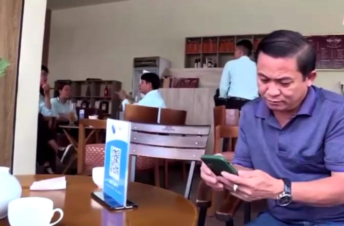 Ông Lê Công Háo ngụ tại (Phường Tân Bình, TP Đồng Xoài) không còn dùng tiền mặt để trả tiền cà phê mà chỉ cần quét mã QR có sẵn tại bàn và nhập số tiền cần thanh toán. Ảnh: SCT BP