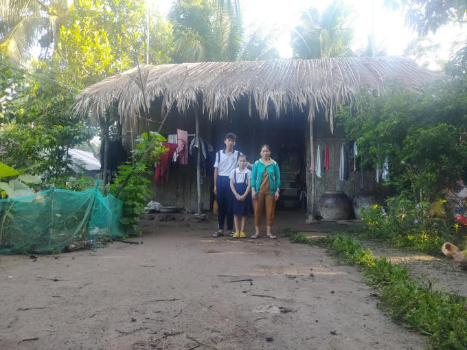 Em T.Q.Đ cùng mẹ và em gái trước căn nhà lá của gia đình.