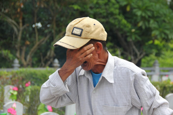 Ông Lê Văn Nguyên khóc nức nở trước bia mộ của anh trai tại nghĩa trang Quốc gia Trường Sơn.