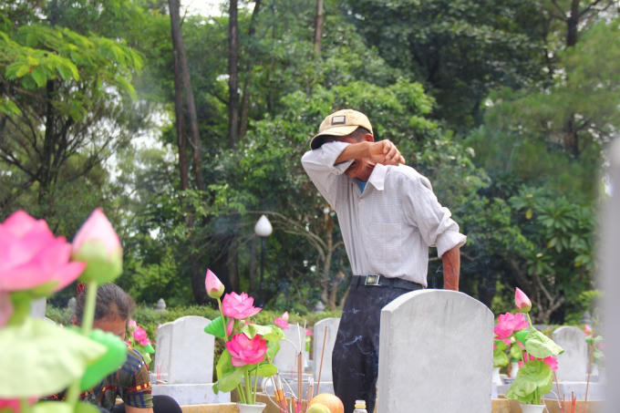 Ông Lê Văn Nguyên khóc nức nở trước bia mộ của anh trai tại nghĩa trang Quốc gia Trường Sơn.