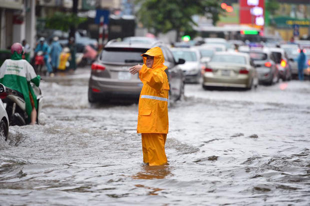 Nhân viên công ty thoát nước hướng dẫn các phương tiện giao thông không đi qua khu vực ngập sâu và cảnh báo các xe hạn chế tốc độ.