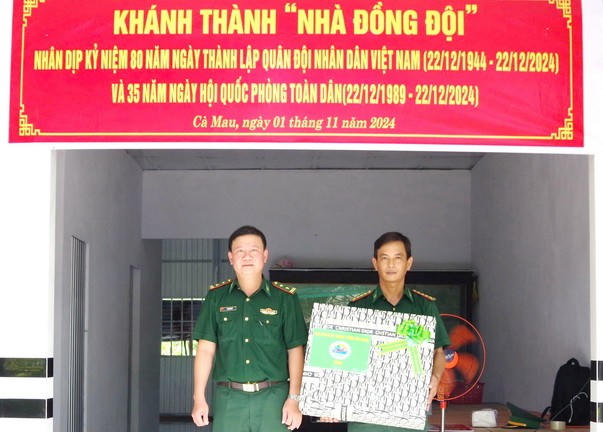 Trung tá Lê Thanh Sử - Chính trị viên Đồn Biên phòng Rạch Gốc tặng quà cho gia đình quân nhân Đại úy Nguyễn Văn Phong.