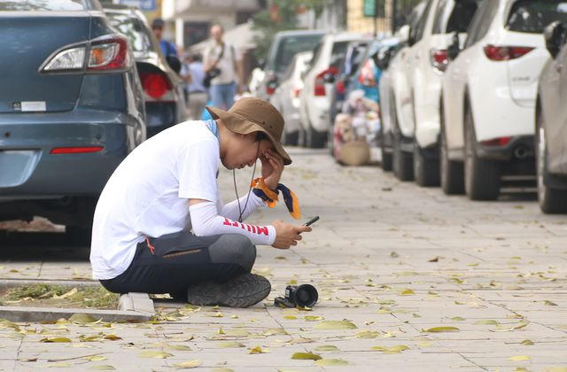 Một phóng viên ngồi nghỉ trên vỉa hè phố Ngô Quyền trong lúc chờ đợi sự kiện diễn ra.