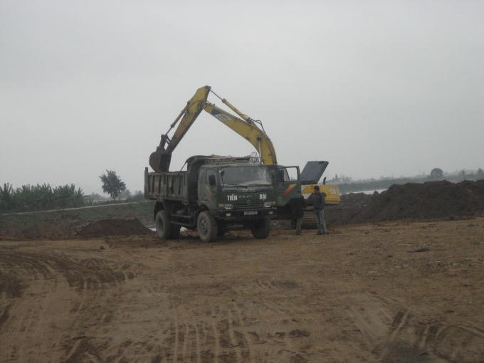 Máy xúc và xe tải tiến hành việc san lấp.