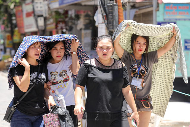 Nắng n&oacute;ng, người đi đường phải t&igrave;m đủ mọi c&aacute;ch che chắn.