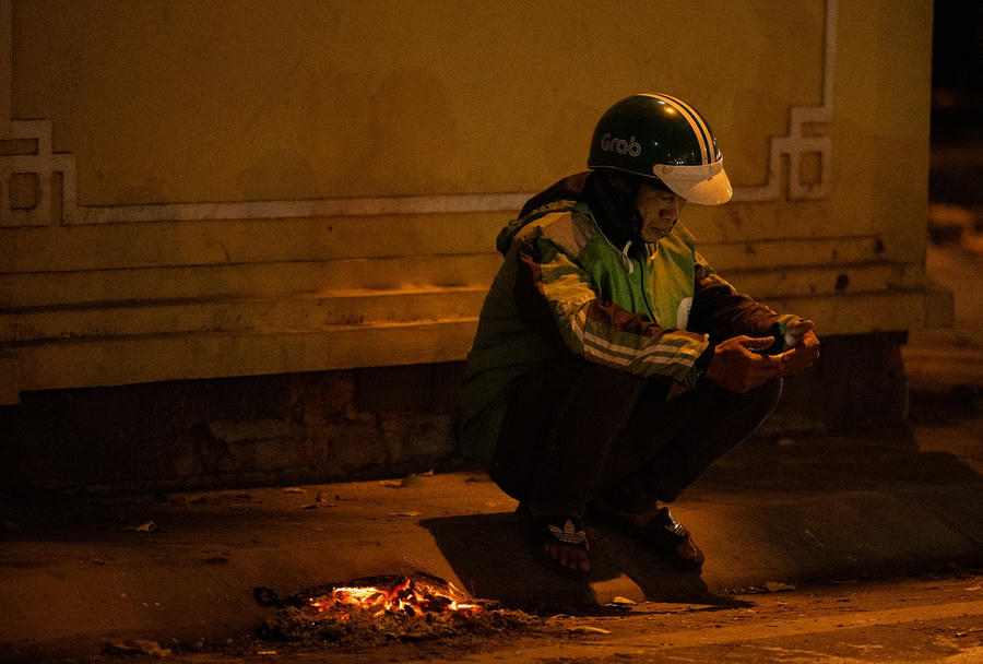Tài xế xe ôm công nghệ trong lúc chờ khách phải đốt lửa sưởi ấm