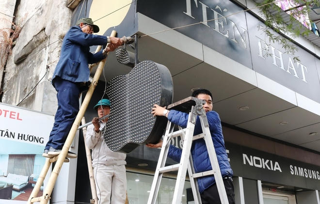 Nhân viên trật tự đô thi đang dùng mắy cắt sắt tháo dỡ "quả táo" của cửa hàng kinh doanh điện thoại trên đường Điện Biên Phủ.
