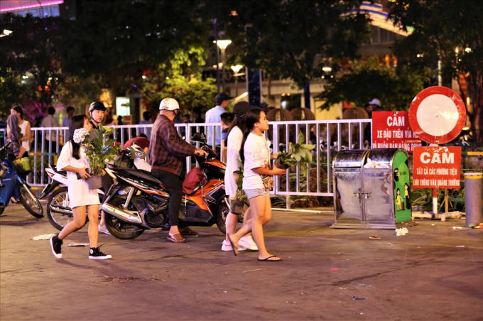 Ở ngoài đường, nhiều người vẫn kiên trì đợi các xe hoa đi ra để lấy những chậu hoa mà mình thấy là còn có thể sử dụng được. Ảnh: Trường Sơn