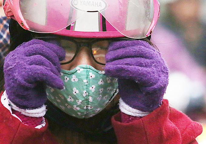 Người phụ nữ lau kính khi dừng đèn đỏ ở ngã tư Tôn Đức Thắng.