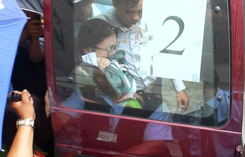 Một trong 2 nhân viên Eximbank bị dẫn giải ra xe vào ngày 26/3. (Nguồn: Người Lao động)