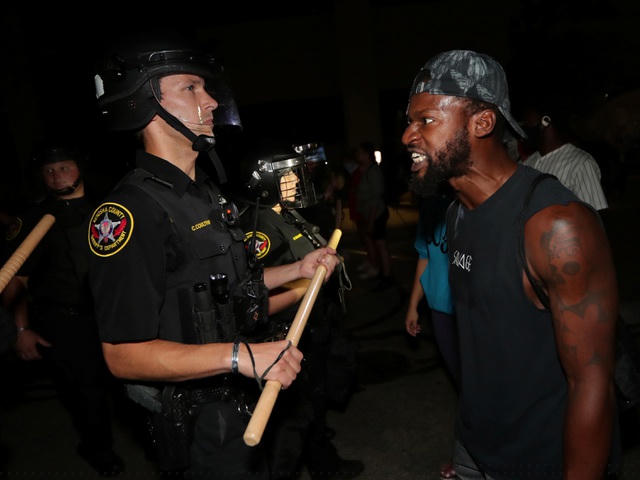 Một người da màu đối đầu với cảnh sát bên ngoài trụ sở tòa án Kenosha. (Ảnh: Reuters)