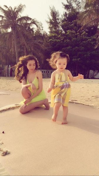Hai mẹ con cùng mặc chiếc váy màu vàng giống nhau, đùa nghịch trên bãi biển. Ảnh: facebook.