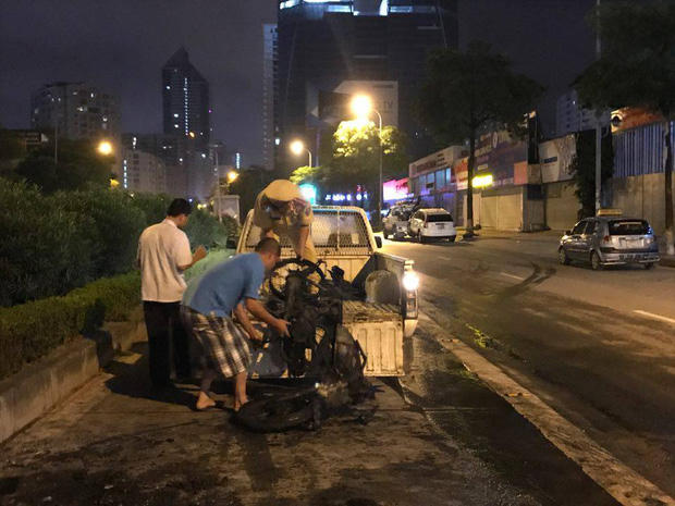 Lực lượng CSGT cùng người dân đưa chiếc xe máy bị cháy rụi lên xe.