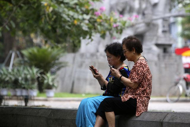 Đôi bạn già đang trao đổi thông tin từ những chiếc điện thoại thông minh.