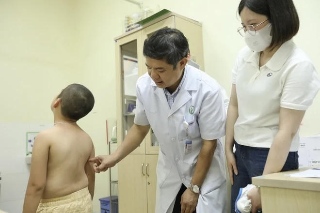 Bác sỹ khám, tư vấn cho bệnh nhi cong vẹo cột sống. (Ảnh: Minh Quyết/TTXVN)