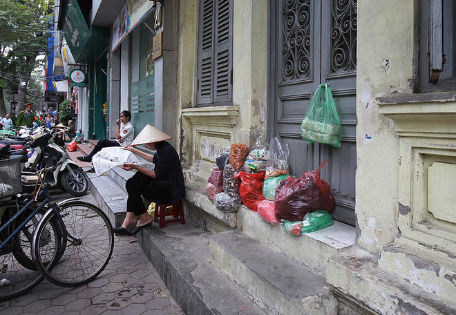 Dẹp bớt bàn ghế, phông bạt, người phụ nữ bán hàng khô bày đồ trên bậc tam cấp của ngồi nhà ở đường Ngô Thì Nhậm.