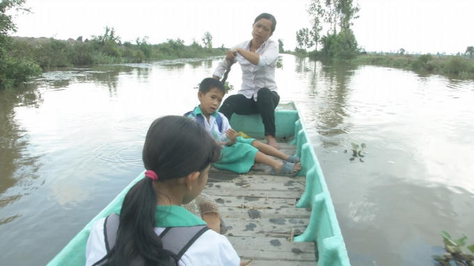 Chị Lê ngoài việc phụ chồng cưa củi, lo toan nhà cửa thì chèo ghe đưa đón hai con đi học hàng ngày.