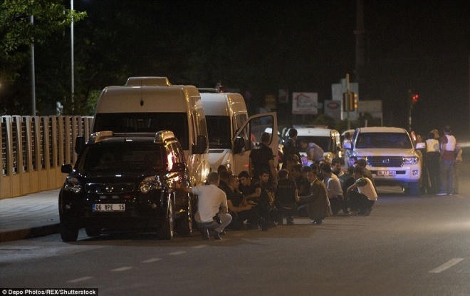 Dân thường nấp sau các xe gần trụ sở đài phát thanh truyền hình Thổ Nhĩ Kỳ sau khi tòa nhà bị trúng bom. Hãng thông tấn nhà nước đưa tin trực thăng quân sự cũng tấn công trụ sở đài truyền hình vệ tinh TURKSAT ở ngoại ô Ankara.  Ảnh: Rex