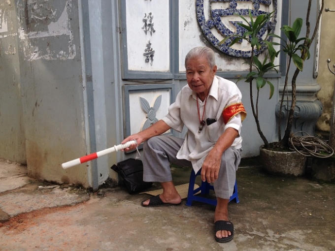 Dù trời nắng hay trời mưa, ông Chính vẫn luôn ra đứng đầu cổng làng điều tiết giao thông. Ảnh: Thảo Nguyên.