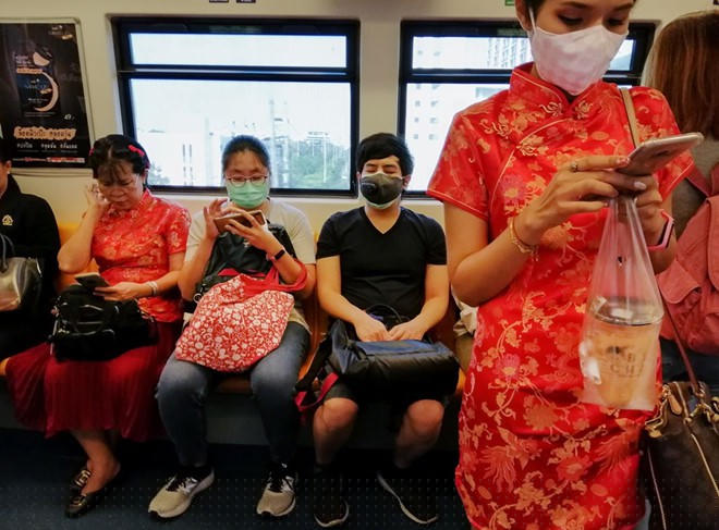 Một phụ nữ đeo khẩu trang mặc áo sườn xám trên chuyến tàu ở thủ đô Bangkok, Thái Lan ngày 24/1. Ảnh: AFP.