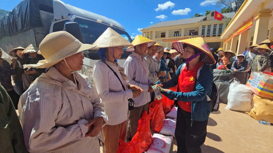 Tình nguyện viên tặng nhu yếu phẩm, tiền mặt cho người dân vùng lũ.
