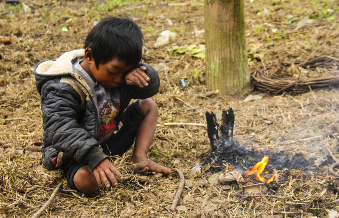 Một đứa trẻ ở bản K-Ai tự đốt lửa để xua đi cái lạnh. (Ảnh: Hải Long).