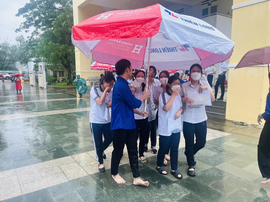 Thí sinh được các tình nguyện viên hỗ trợ khi trời mưa lớn.