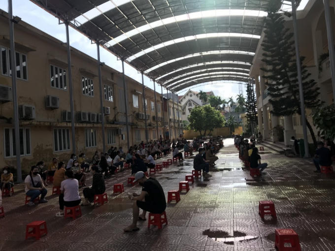 Phụ huynh học sinh Trường Tiểu học An Dương, huyện An Dương ngồi giữ khoảng cách trong giờ đợi con.