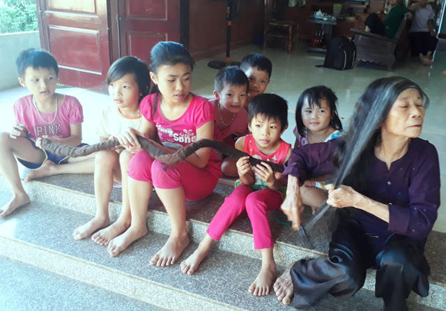 Các cháu nhỏ vui đùa bên mái tóc kỳ lạ của cụ Nghiên.