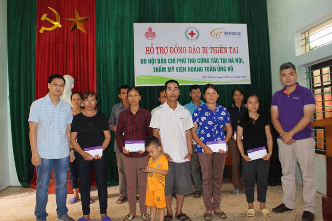 Ông Hoàng Minh Thành, Phó tổng biên tập của tạp chí Thương Hiệu và Pháp luật (ngoài cùng bên trái) cùng ông Bùi Mạnh Anh, đại diện thẩm mỹ viện Hoàng Tuấn trao quà cho bà con vùng lũ thuộc xã Mỹ Thuận.