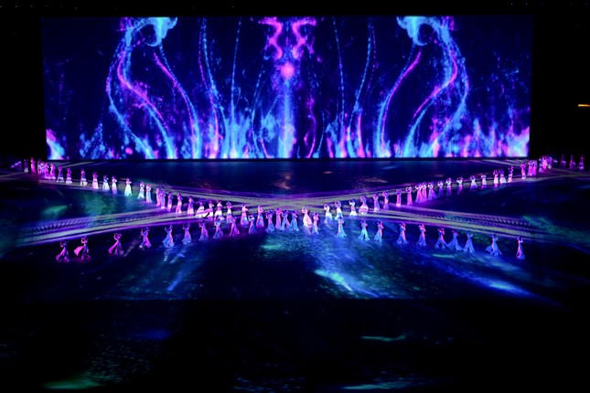 Khoảng hơn 200 diễn viên múa với áo dài và nón LED trình diễn trên nền nhạc violin và đàn bầu.