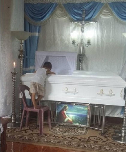 BéKhayne chốc chốclại trèo lên nhìn mẹ bên trong quan tài.Ảnh letribunaldunet.