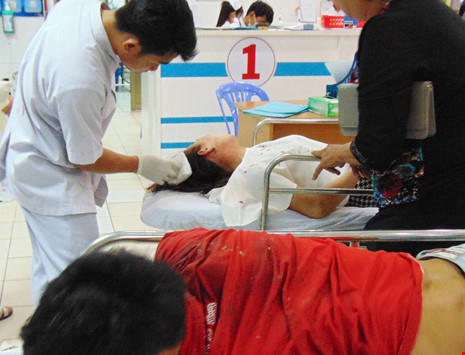 Nhân viên cấp cứu khám vết thương đầu của một phụ nữ bị tai nạn. Ảnh: TRẦN NGỌC