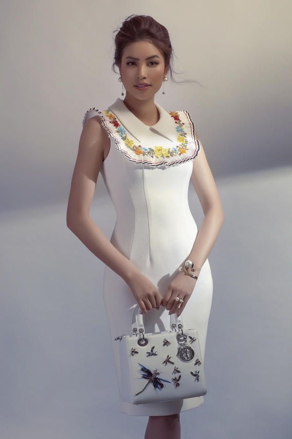 Váy trắng tối giản có điểm nhấn tay áo hình cánh hoa cúc và điểm xuyết chi tiết hoa đính kết 3D dọc theo cổ thuyền được Phạm Hương kết hợp với túi xách cùng màu đính hoạ tiết chuồn chuồn bằng đá cực kỳ sang trọng và thanh lịch.