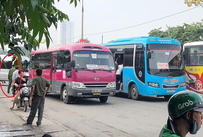 Xe khách dàn hàng ngang bắt khách trên đường nhưng một cán bộ công an (vòng tròn) làm việc tại cổng bến Giáp Bát sáng 20/8 chỉ đứng nhìn.