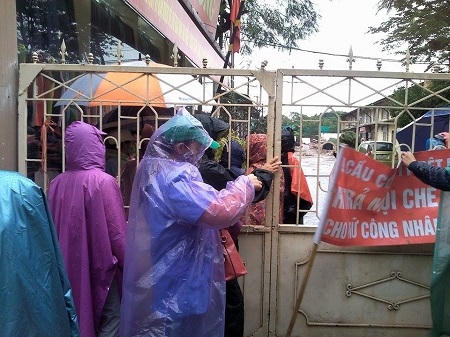 Những công nhân bên trong và bên ngoài bị ngăn cách bởi cánh cổng do Công ty Dệt khóa.