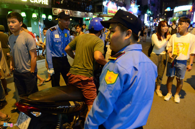 Một chiếc xe máy chạy vào đường đi bộ bị lực lượng chức năng nhắc nhở. Chủ xe đã phải xuống để dắt bộ.