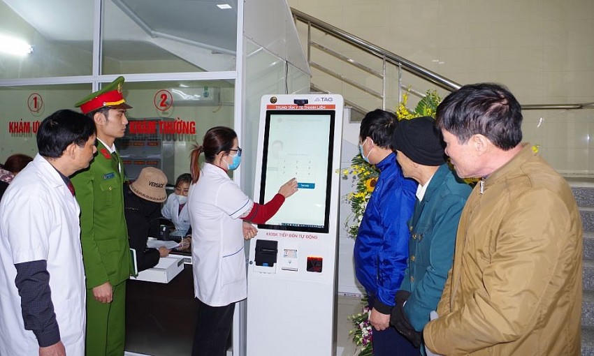 Cán bộ Công an và nhân viên y tế hướng dẫn người dân sử dụng KIOSK đăng ký khám bệnh tự động sử dụng căn cước công dân gắn chíp và nhận diện khuôn mặt. Ảnh: Ánh Tuyết