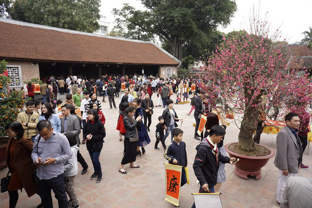 Ngày mùng 2 Tết, khu di tích Văn Miếu - Quốc Tử Giám đông nghịt người từ sáng sớm. Trong thời tiết thuận lợi, người dân Hà Nội tranh thủ đến trường đại học đầu tiên của Việt Nam để du xuân, cầu mong những điều tốt đẹp cho một năm mới.