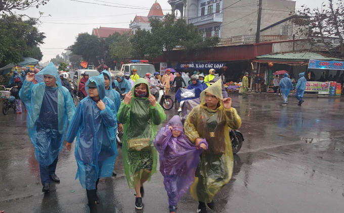 Các du khách đến với chợ Viềng phải mặc áo mưa chống lại cơn mưa nặng hạt chiều nay.