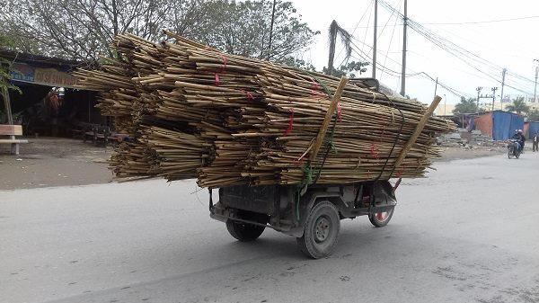 Một xe 3 bánh tự chế chở hàng quá khổ đang lưu thông trên đường.