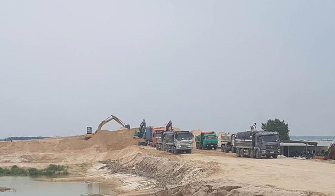 Xe chở cát cỡ lớn có nối đuôi nhau hoạt động tại bãi cát trong lòng hồ Dầu Tiếng.