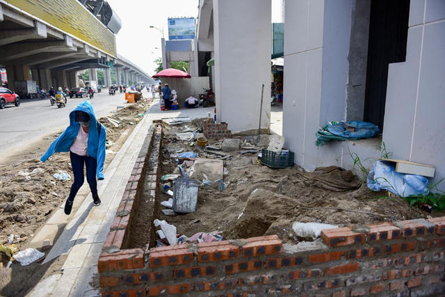 Phía dưới một lối dẫn lên nhà ga đường sắt trên cao, phần vỉa hè còn lại cho người đi bộ rất hẹp.
