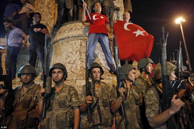 Binh sĩ đứng gác ở quảng trường Taksim tại Istanbul, trong lúc những người ủng hộ Tổng thống Erdogan mang theo quốc kỳ phản đối đảo chính. Ảnh: AP