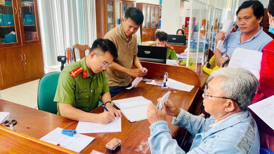 Thành viên Đội hình thanh niên tình nguyện Công an tỉnh Cà Mau hỗ trợ người già yếu và người dân thực hiện các thủ tục hành chính.