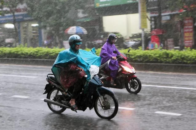 Người Hà Nội trang bị 2 áo mưa, vội vã trở về nhà trong mưa bão. (Ảnh: Quý Đoàn)