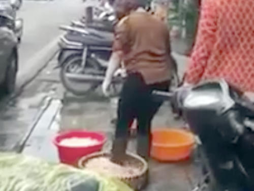 Người phụ nữ đi ủng khuấy, đảo lòng lợn trong thúng. (Ảnh cắt từ clip).