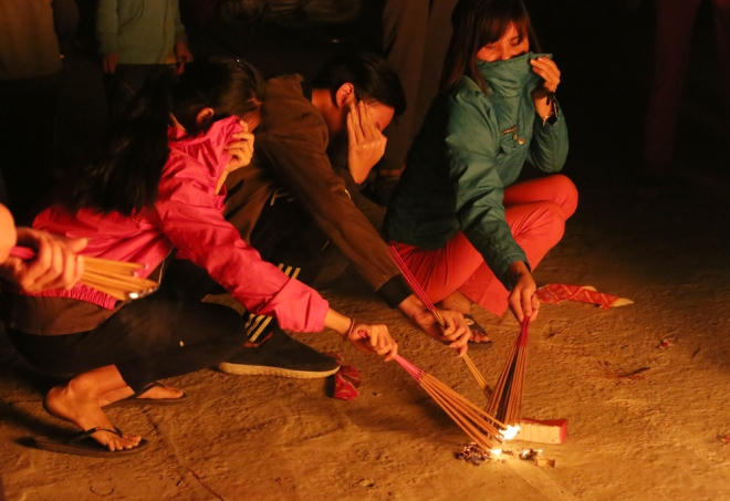 Áo rét, khẩu trang, mũ nón, tay che mặt chống lại cái nóng phát ra từ đống lửa lớn.