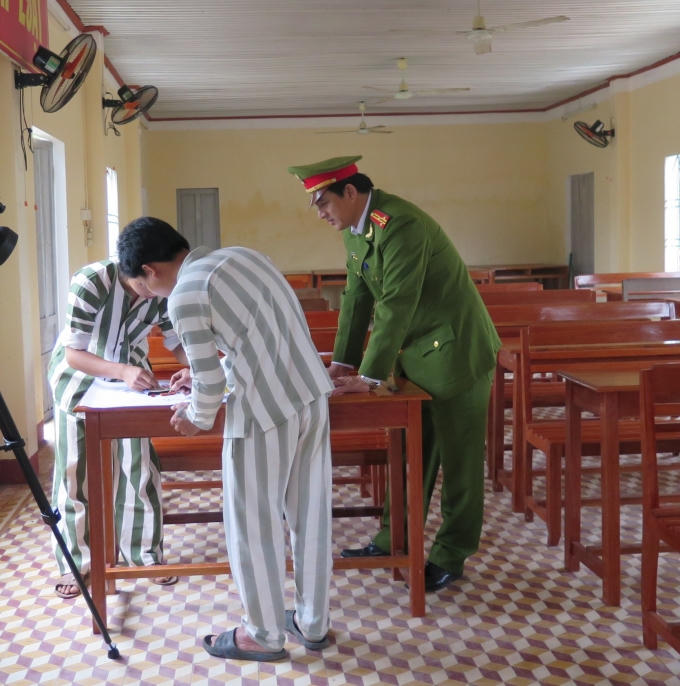 Thượng tá Nguyễn Thành Nhân - Giám thị trại giam đang hướng dẫn phạm nhân làm báo tường (ảnh: Phương Nam).