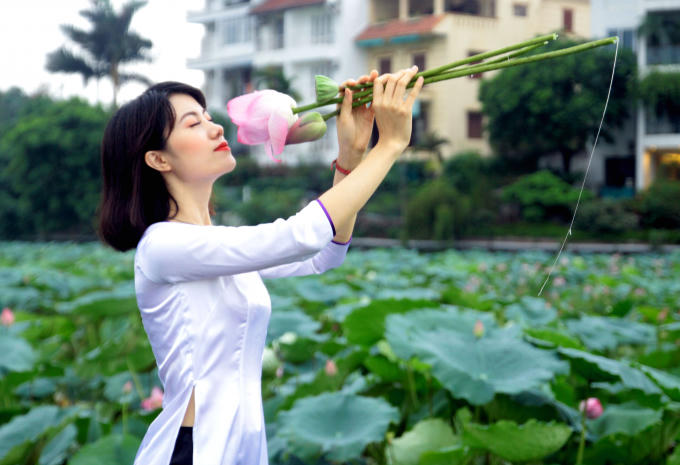 Ào dài trắng tinh khôi làm nổi bật những cánh sen hồng khoe sắc.